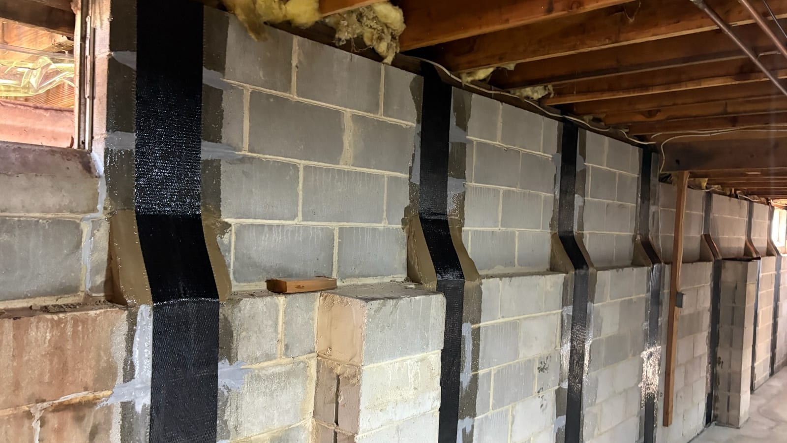 Vertical reinforcement installed along an existing masonry foundation wall.